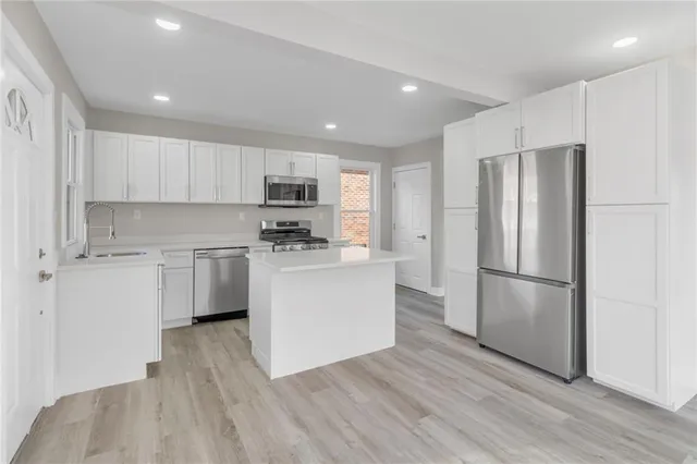 a kitchen with a refrigerator a white stove top oven and white cabinets with wooden floor