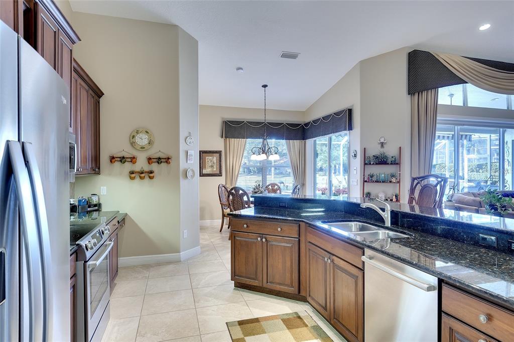 11809 Oak Ridge Drive Parrish, FL 34219 - Photo 14 of 39 a kitchen with stainless steel appliances granite countertop a sink stove and cabinets