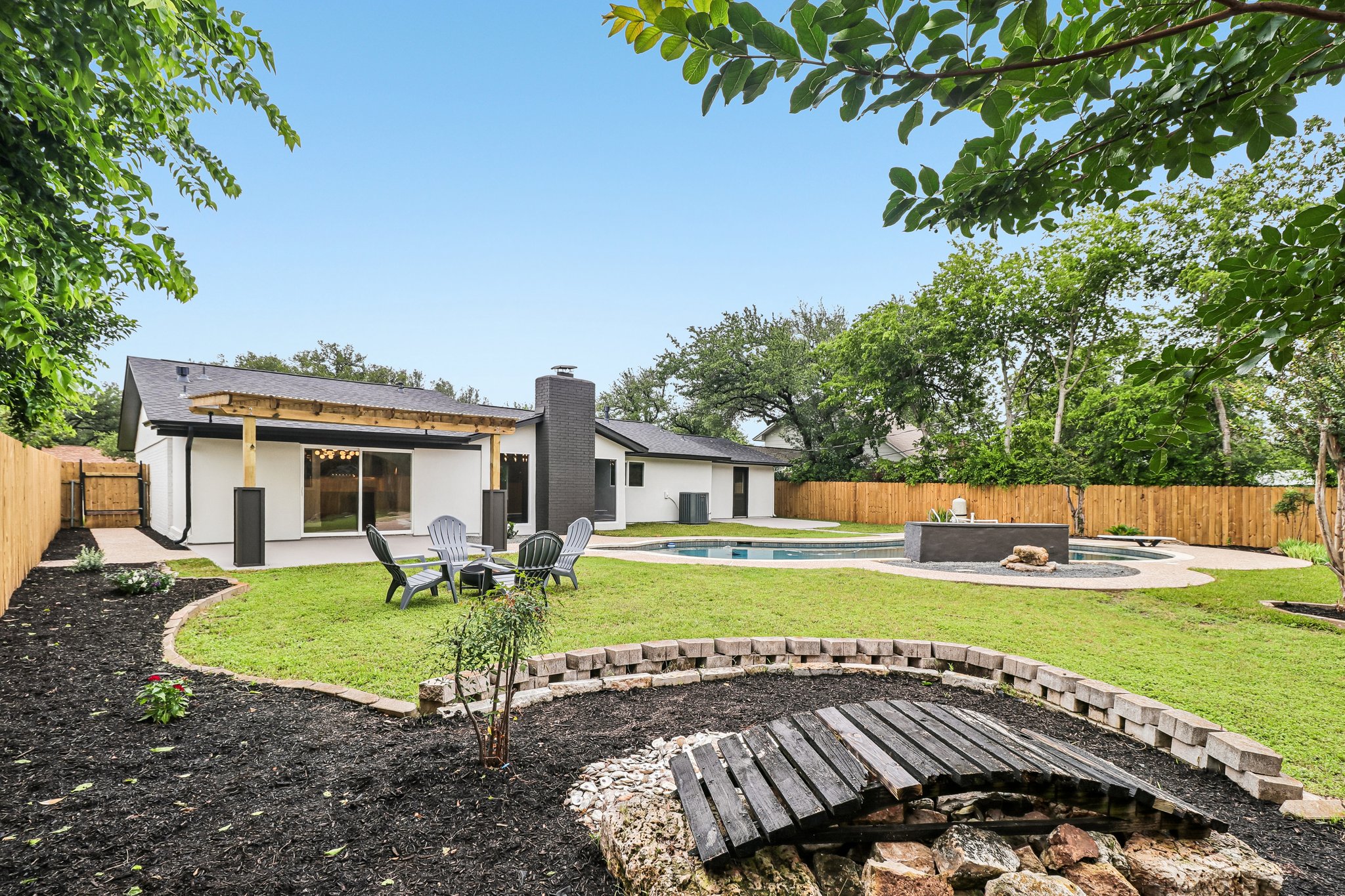 11809 Charing Cross Road Austin, TX 78759 - Photo 25 of 34 Lush landscaping surrounds a private backyard oasis with a sparkling pool and charming bridge feature.