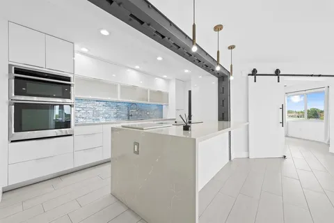 a large white kitchen with a sink stainless steel appliances and cabinets