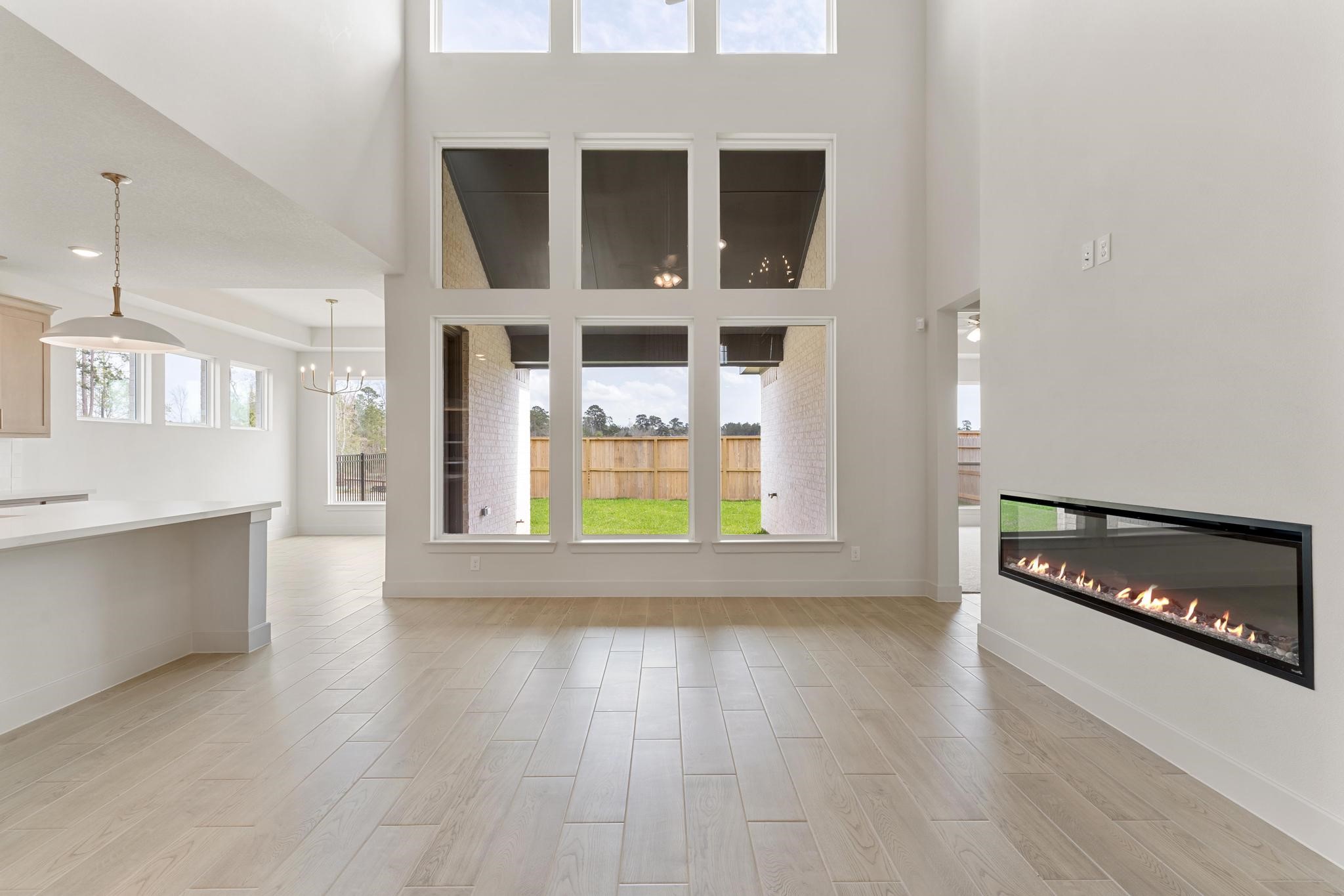 407 Mathis Lk Court Conroe, TX 77304 - Photo 2 of 26 Wall of windows allow natural light into your living room which is centrally located between the kitchen and dining area making it perfect for gathering and entertaining.