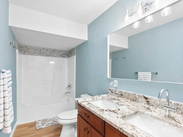a bathroom with a granite countertop sink a toilet a mirror and bathtub