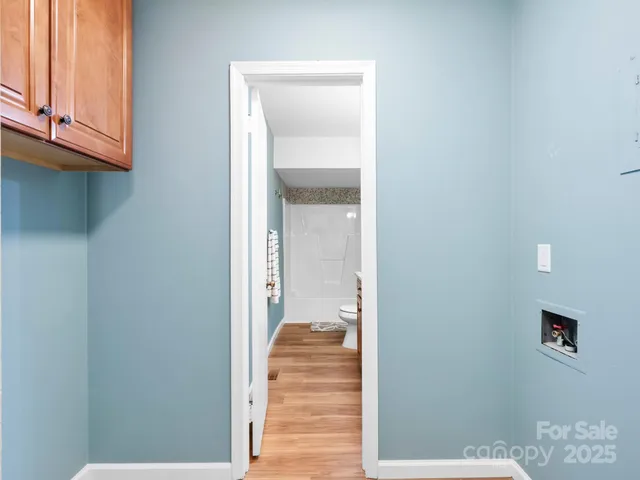 a view of a hallway with wooden floor and a bathroom