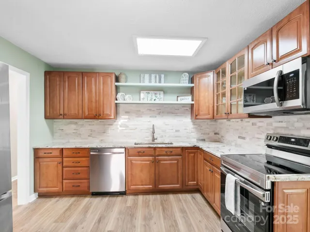 a kitchen with stainless steel appliances granite countertop wooden cabinets granite counter tops and a hard wood floors