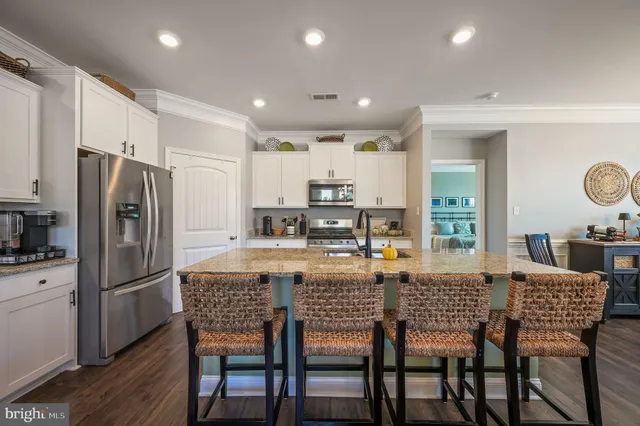 a kitchen with stainless steel appliances granite countertop a dining table chairs refrigerator and microwave