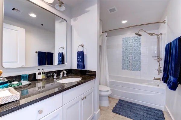 a bathroom with a granite countertop tub sink and mirror