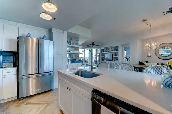 a kitchen with stainless steel appliances granite countertop a sink a refrigerator and a white cabinets