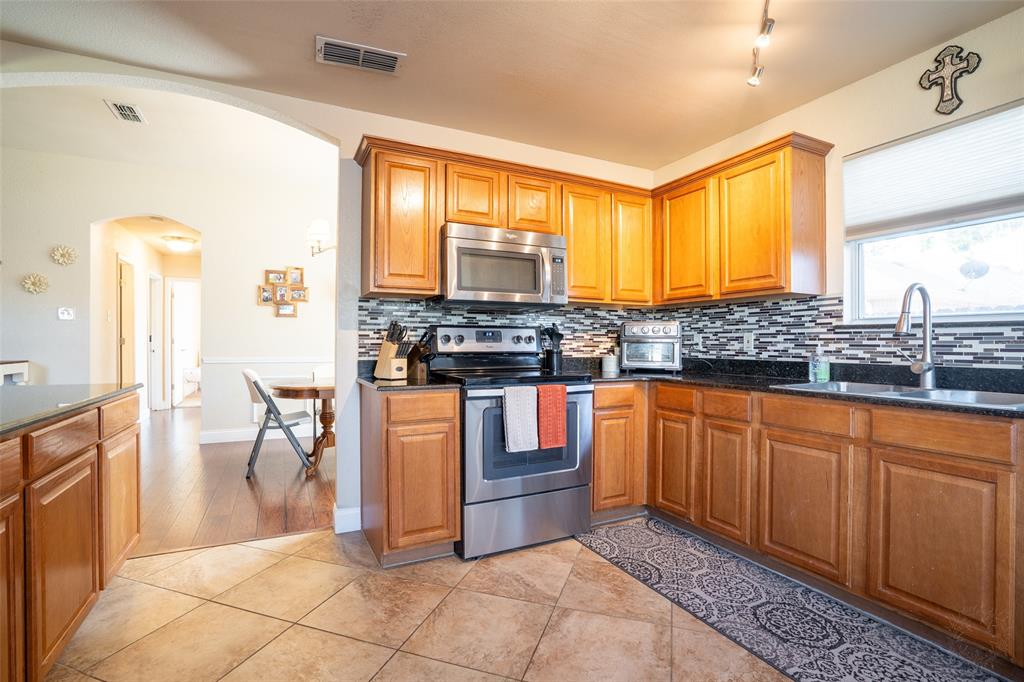 2924 Meandering Way Granbury, TX 76049 - Photo 10 of 40 a kitchen with stainless steel appliances granite countertop a stove a sink and a microwave