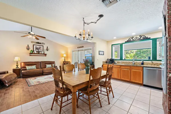 a dining room with wooden floor a chandelier a wooden table and chairs