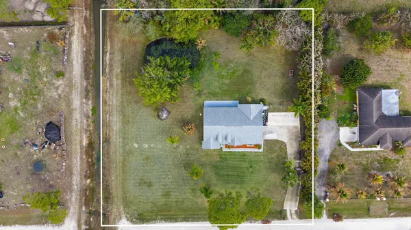 an aerial view of a house with swimming pool and large trees