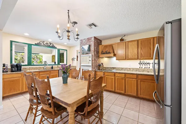 a kitchen with stainless steel appliances granite countertop a refrigerator a sink dishwasher a dining table and chairs with wooden floor