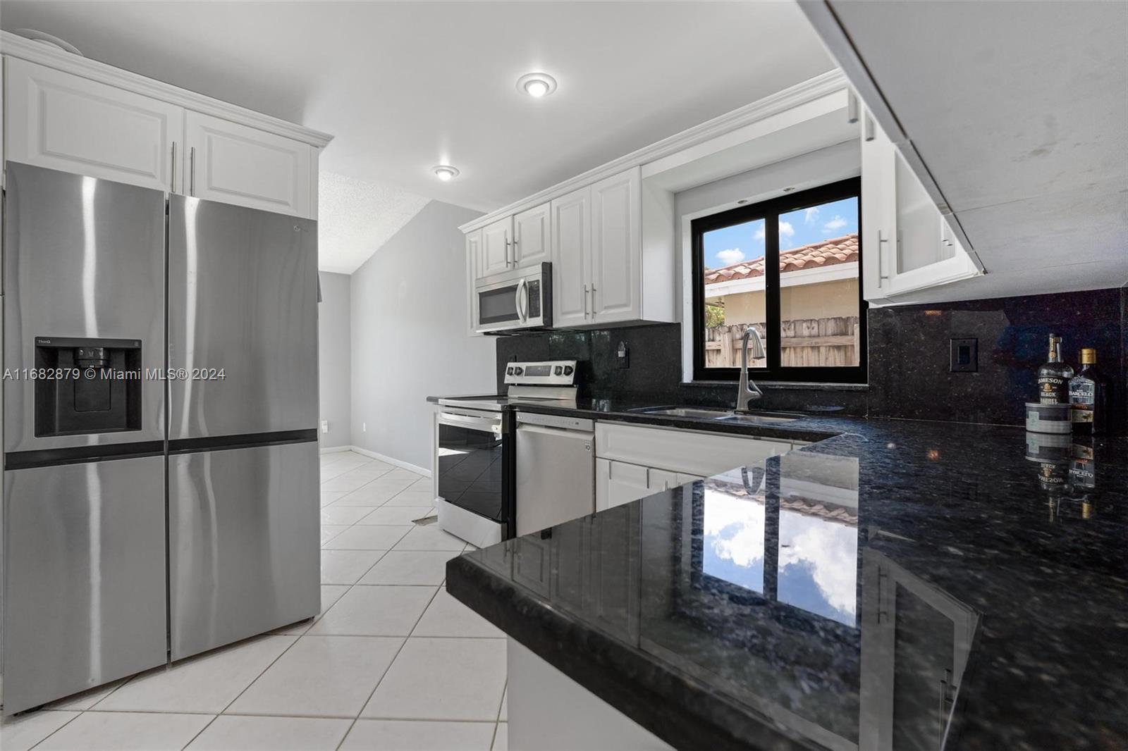 14006 Southwest 48th Terrace Miami, FL 33175 - Photo 20 of 24 a kitchen with stainless steel appliances granite countertop a refrigerator a stove and a sink with wooden cabinets