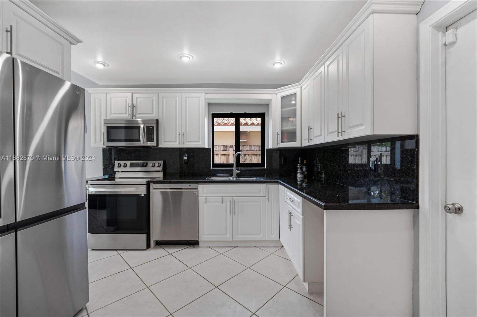 14006 Southwest 48th Terrace Miami, FL 33175 - Photo 21 of 24 a kitchen with stainless steel appliances granite countertop a refrigerator a stove a sink and white cabinets