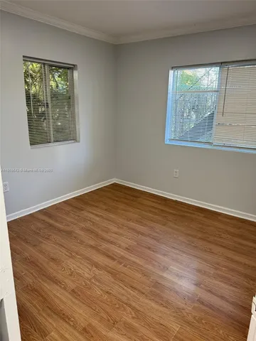 a view of an empty room with wooden floor and window