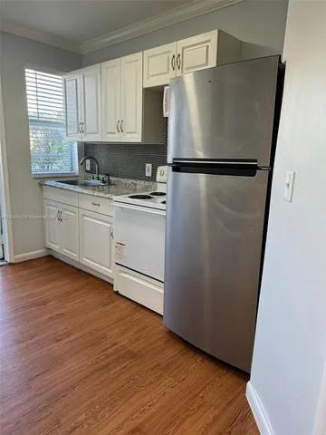 a kitchen with stainless steel appliances granite countertop a refrigerator sink and white cabinets
