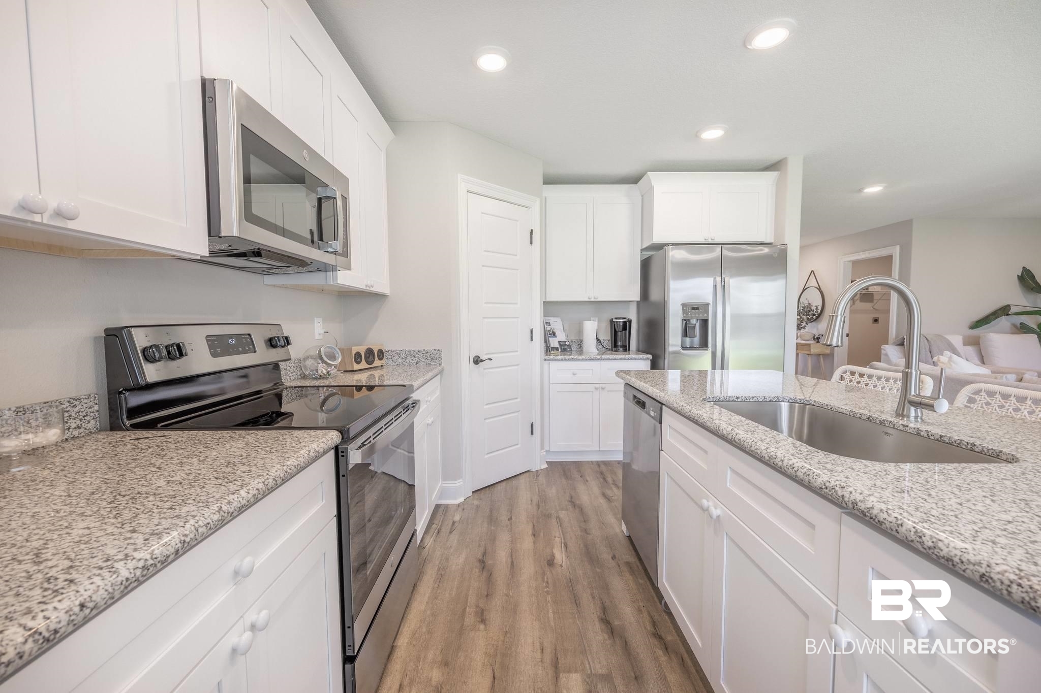 12918 Flanagan Street Elberta, AL 36530 - Photo 22 of 33 Modern kitchen featuring white cabinetry, granite-finish countertops, and wood-finish flooring