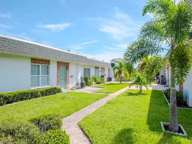 a view of a house with a big yard plants and large trees