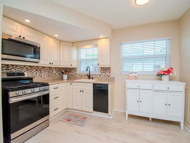 a kitchen with white cabinets appliances and a sink