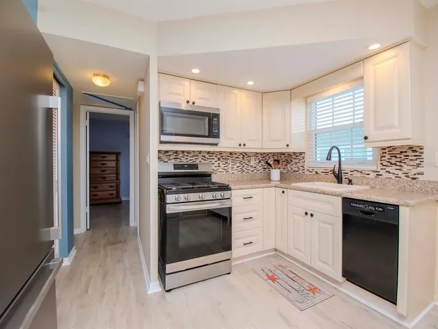 a kitchen with stainless steel appliances granite countertop a stove microwave and sink
