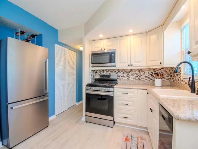 a kitchen with white cabinets and stainless steel appliances