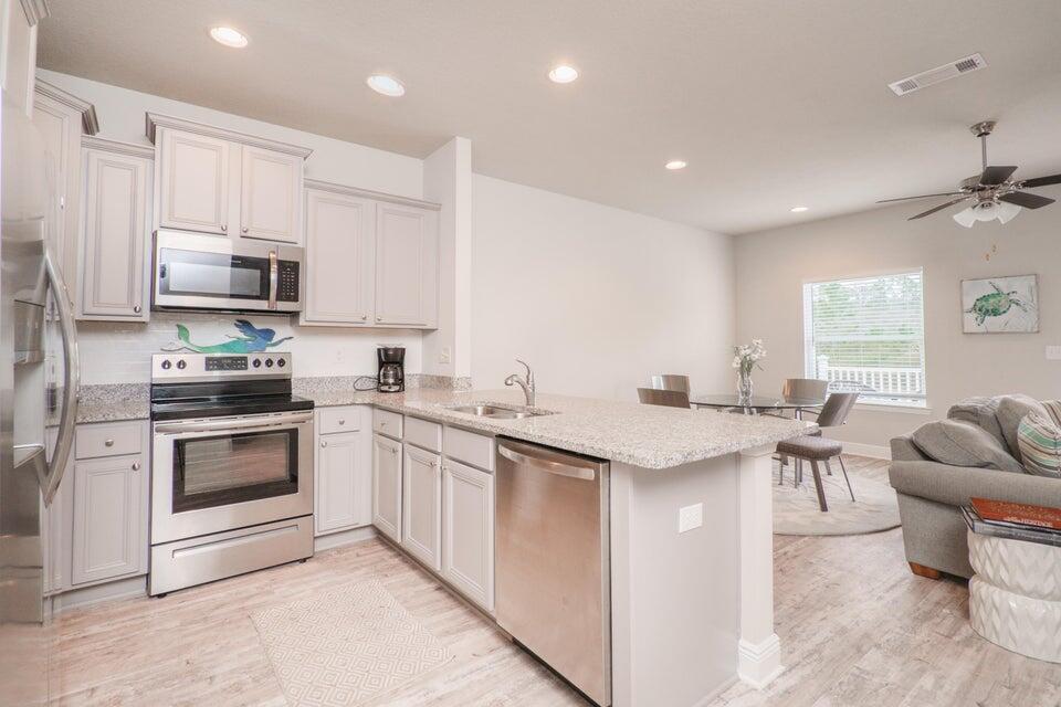 90 Crossing Lane, Unit B Santa Rosa Beach, FL 32459 - Photo 5 of 23 a kitchen with stainless steel appliances granite countertop a stove top oven a sink dishwasher a dining table and chairs with wooden floor