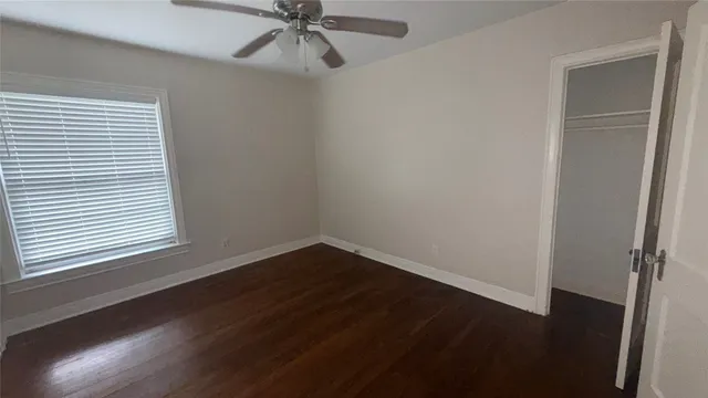an empty room with wooden floor closet and windows