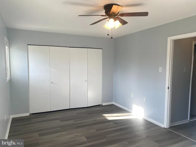 an empty room with wooden floor closet fan and windows