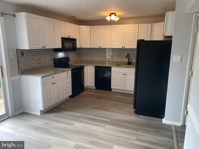 a kitchen with granite countertop white cabinets a refrigerator and a stove