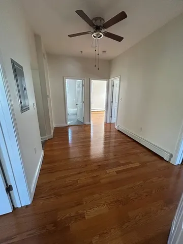 a view of an empty room with a window and wooden floor
