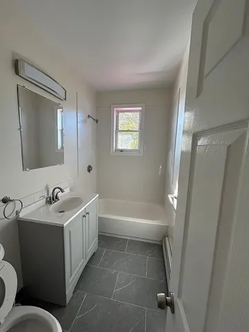 a bathroom with a double vanity sink toilet mirror and bathtub