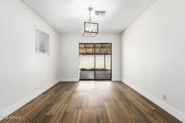 an empty room with wooden floor cabinet and windows