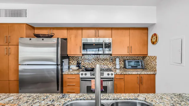 a kitchen with stainless steel appliances kitchen island granite countertop a refrigerator and a stove