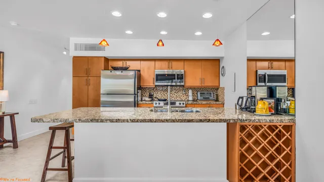 a kitchen with stainless steel appliances granite countertop a sink and a refrigerator
