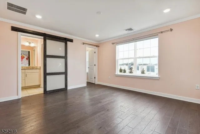 an empty room with wooden floor cabinet and windows