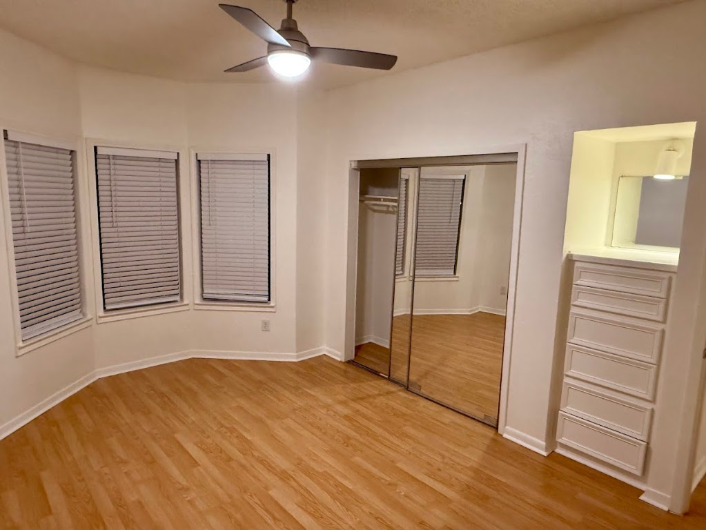 915 West 23rd Street, Unit 108 Austin, TX 78705 - Photo 7 of 15 Unfurnished bedroom featuring light wood-type flooring, a ceiling fan, and a closet
