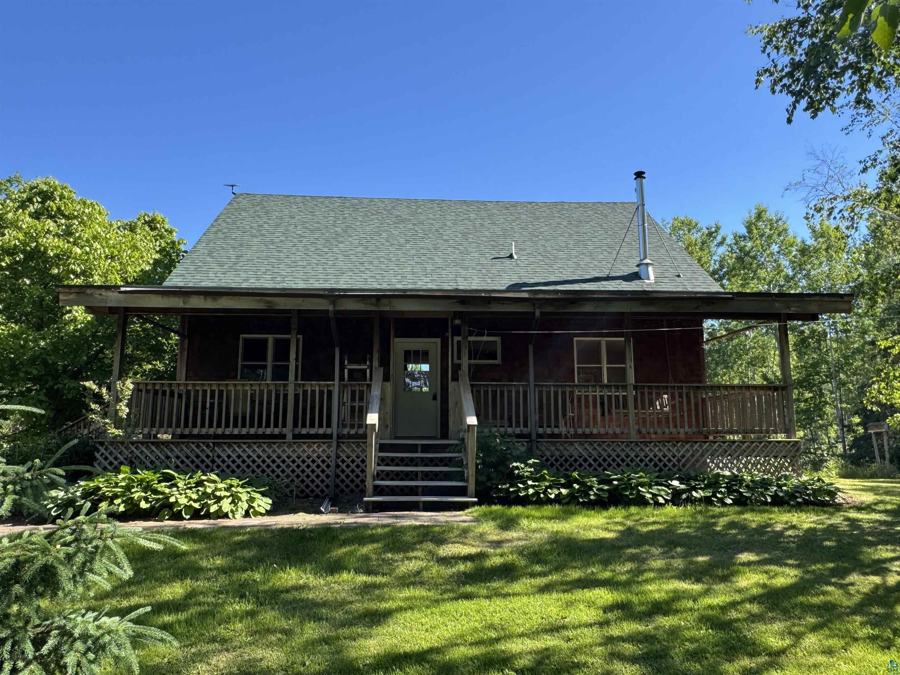 1745 Becks Road Maple, WI 54854 - Photo 2 of 50 Wood-sided cabin featuring a covered porch with wood railings and lattice skirting