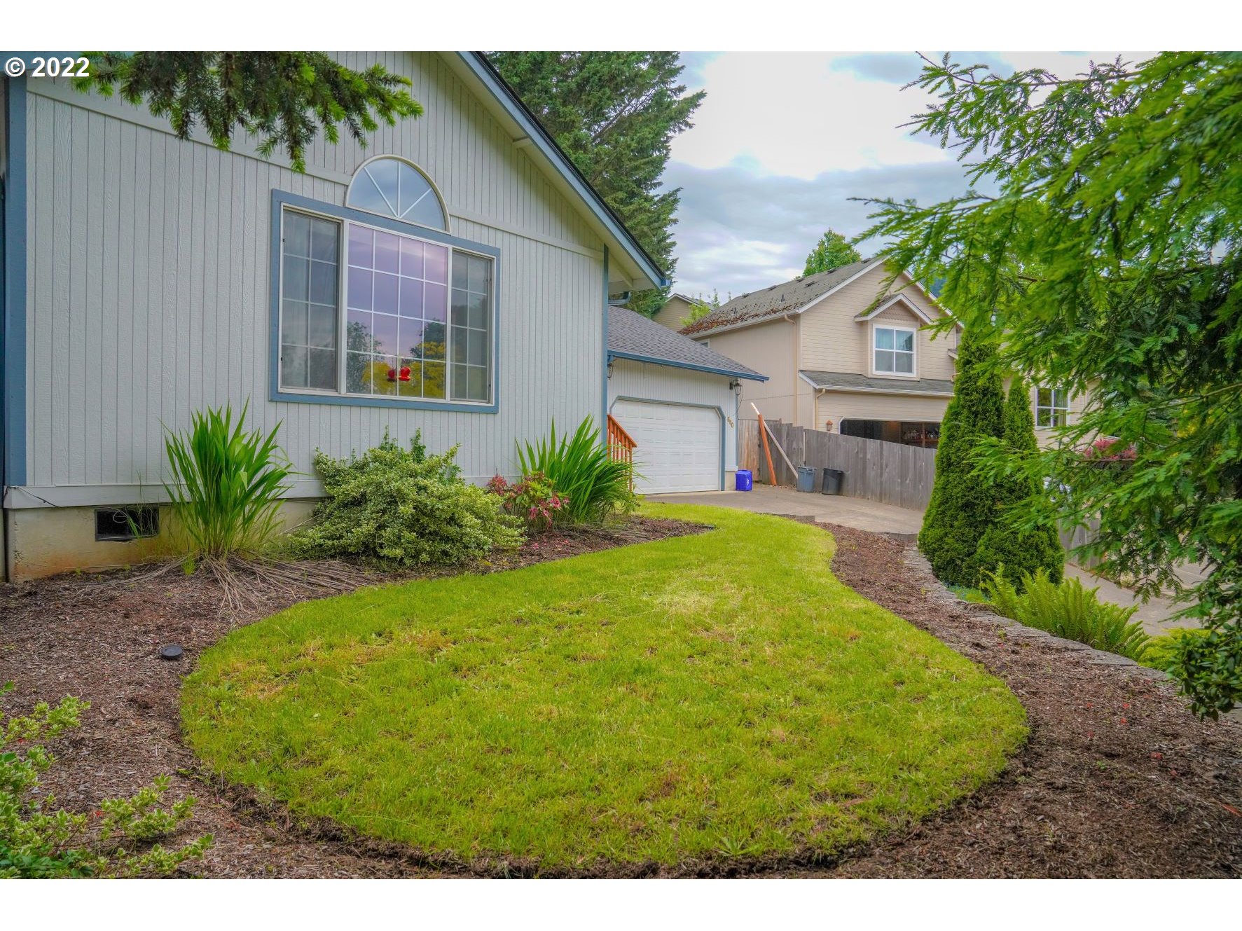 560 South 70th Street Springfield, OR 97478 - Photo 21 of 21 a view of a white house with a small yard plants and a large tree