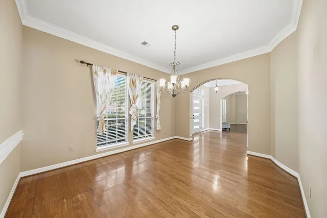 a view of an empty room with window and wooden floor