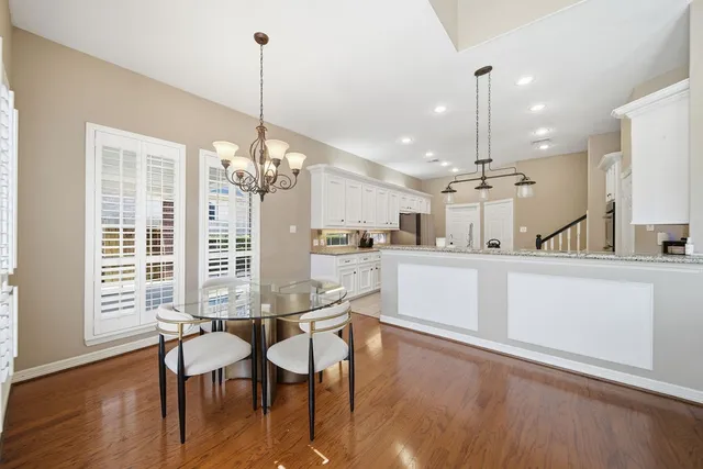 a view of a dining room and livingroom with furniture wooden floor kitchen chandelier