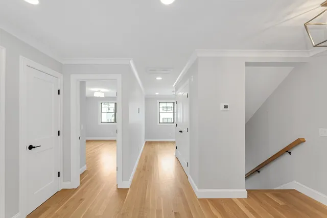 a view of a hallway with wooden floor and a bathroom