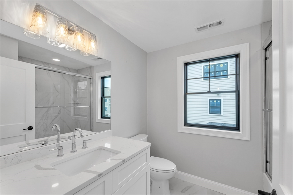 10 Starling Street Boston, MA 02132 - Photo 20 of 36 a bathroom with a toilet a sink a mirror and a window