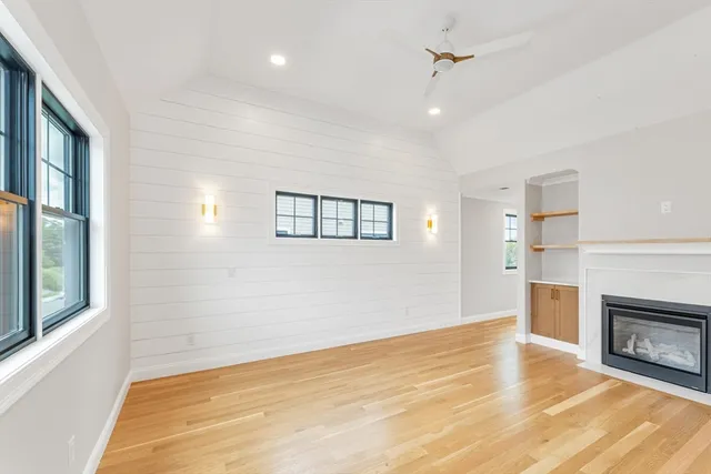 wooden floor in an empty room with a fireplace and a window