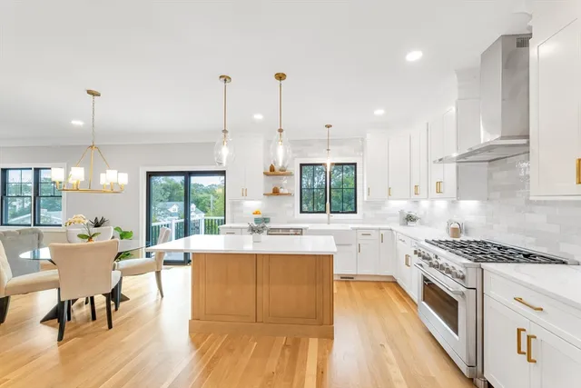 a kitchen with a stove a sink and white cabinets with wooden floor