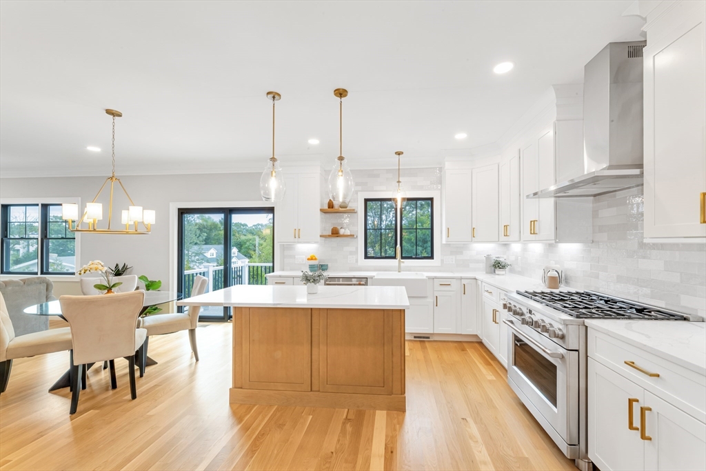 10 Starling Street Boston, MA 02132 - Photo 9 of 36 a kitchen with a stove a sink and white cabinets with wooden floor