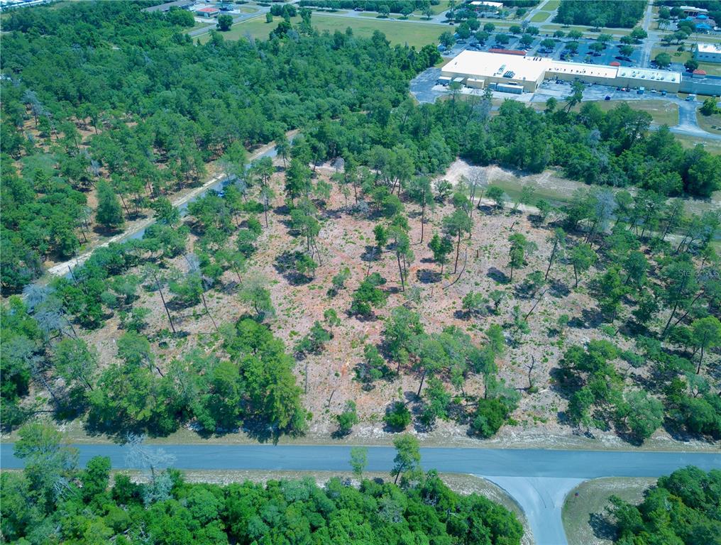 an aerial view of residential house with outdoor space and trees all around