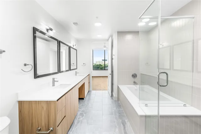 a bathroom with a double vanity sink a mirror and a bathtub