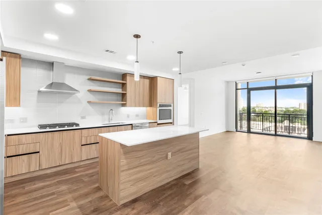 a large kitchen with stainless steel appliances a large counter top and a wooden floors