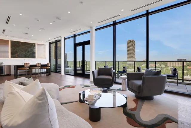 a living room with furniture kitchen view and a large window