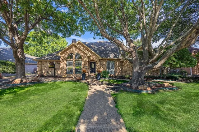 a front view of a house with garden and trees