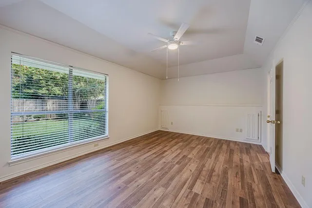 a view of an empty room with wooden floor and a window